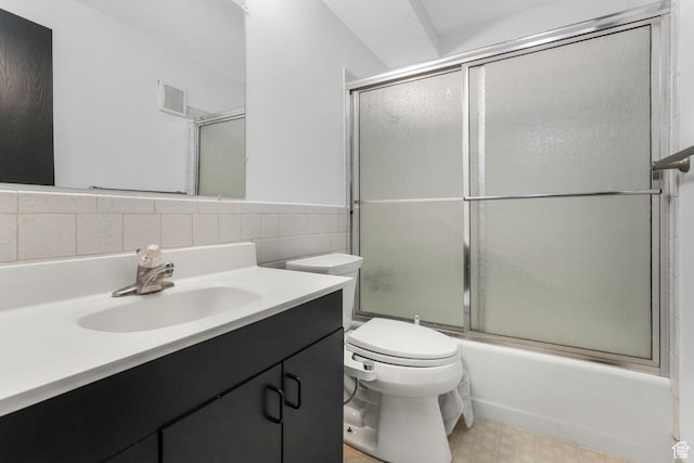 full bathroom with visible vents, toilet, shower / bath combination with glass door, vanity, and tile walls