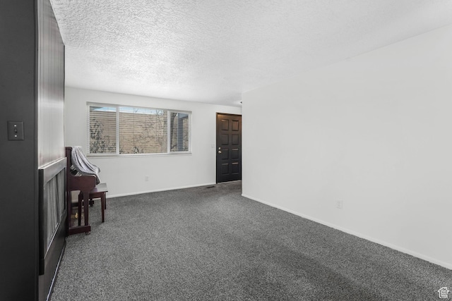 interior space with baseboards, dark carpet, and a textured ceiling