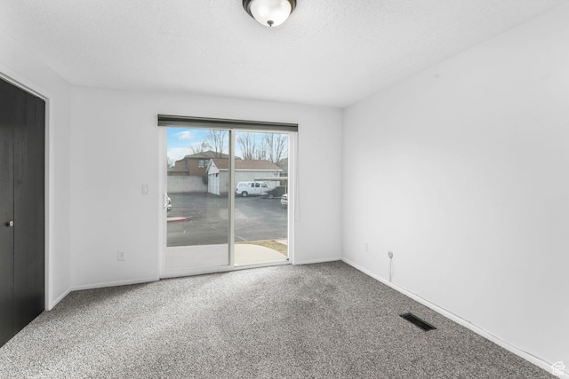 carpeted spare room featuring visible vents, a textured ceiling, and baseboards