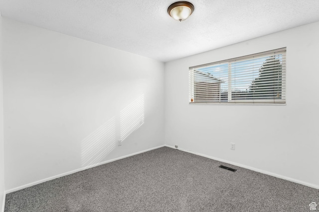 spare room featuring baseboards, a textured ceiling, visible vents, and carpet flooring