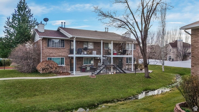 rear view of house with brick siding, fence, stairs, a lawn, and a chimney