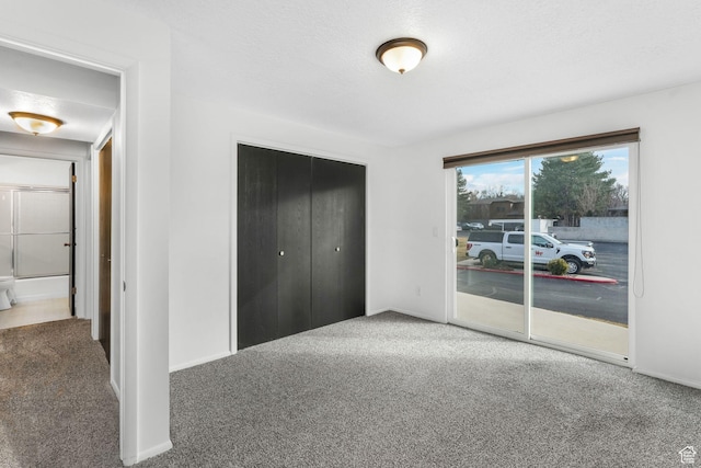 unfurnished bedroom featuring access to exterior, carpet, a closet, and a textured ceiling