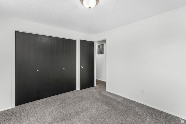 unfurnished bedroom featuring a textured ceiling, a closet, carpet, and baseboards