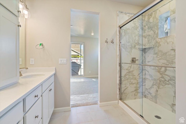 bathroom with baseboards, vanity, a marble finish shower, and a textured ceiling