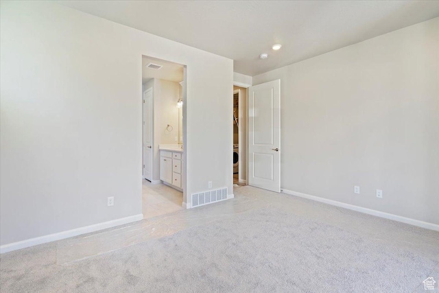unfurnished bedroom featuring baseboards, connected bathroom, visible vents, and light colored carpet
