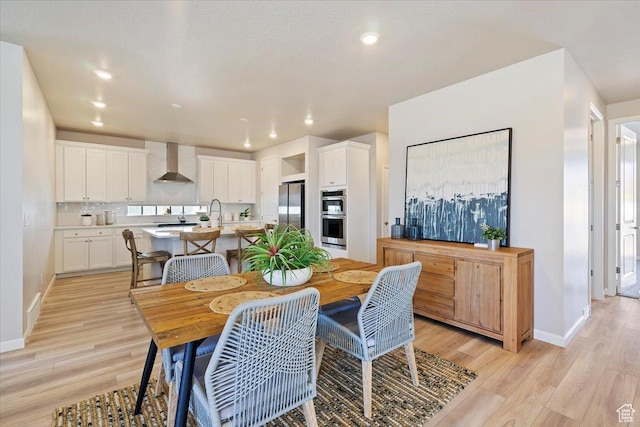 dining room with light wood finished floors, baseboards, and recessed lighting