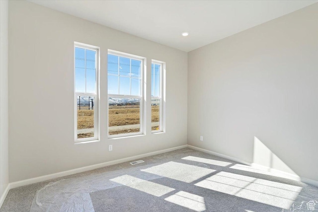 carpeted spare room featuring recessed lighting, visible vents, and baseboards