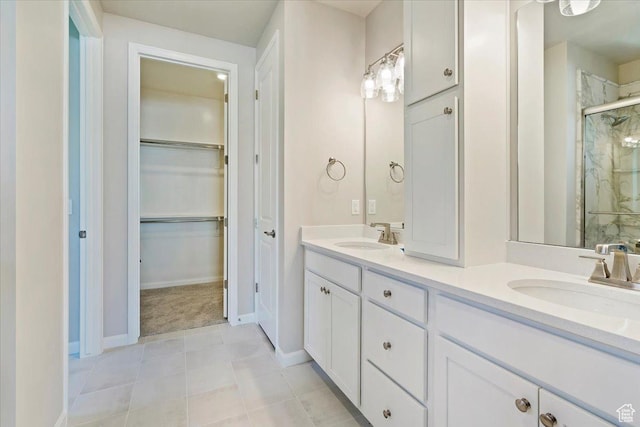 full bathroom with double vanity, a sink, a marble finish shower, and a walk in closet