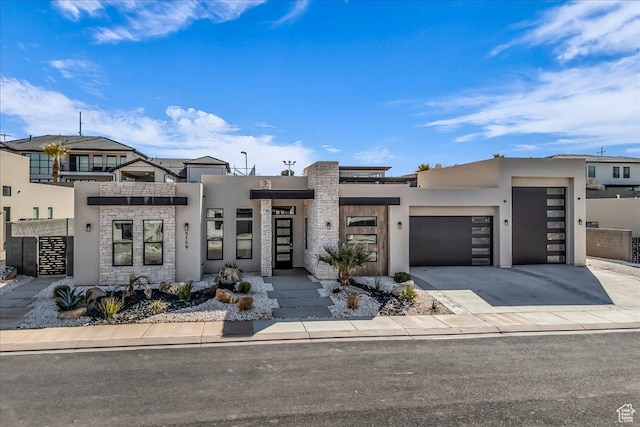 contemporary home featuring a garage, stone siding, driveway, and stucco siding