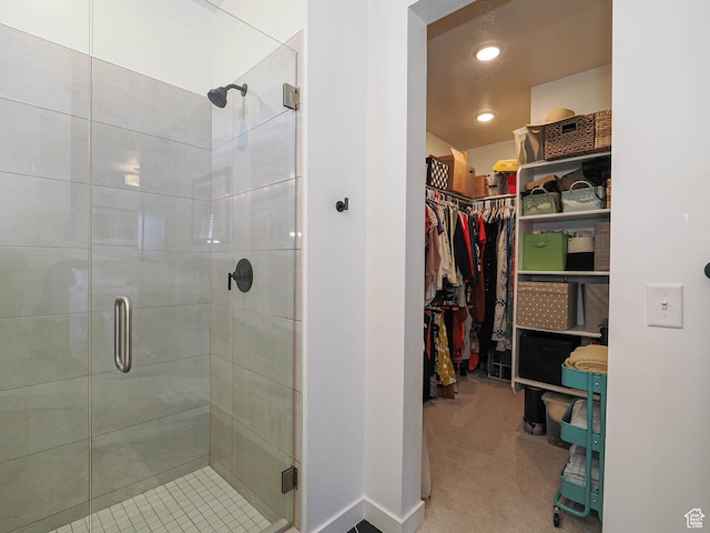 full bath with a stall shower, a spacious closet, and recessed lighting