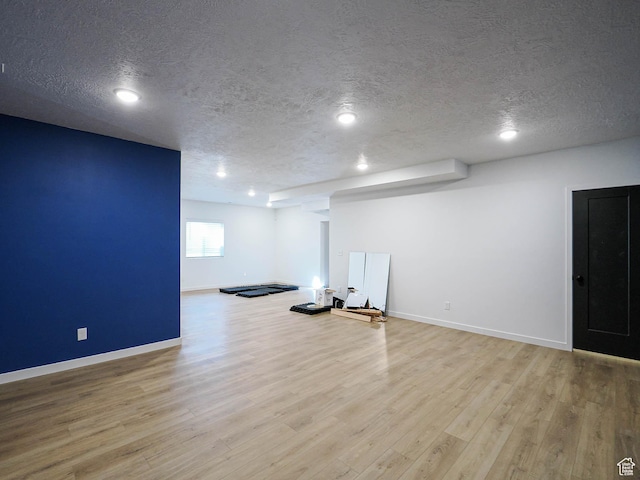 below grade area featuring a textured ceiling, baseboards, and wood finished floors