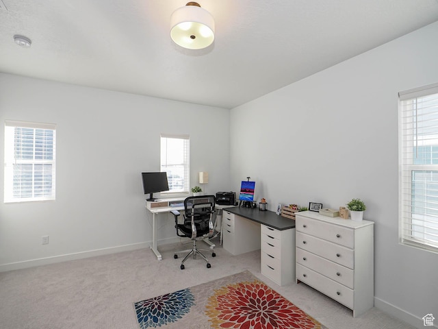 office area featuring light carpet and baseboards