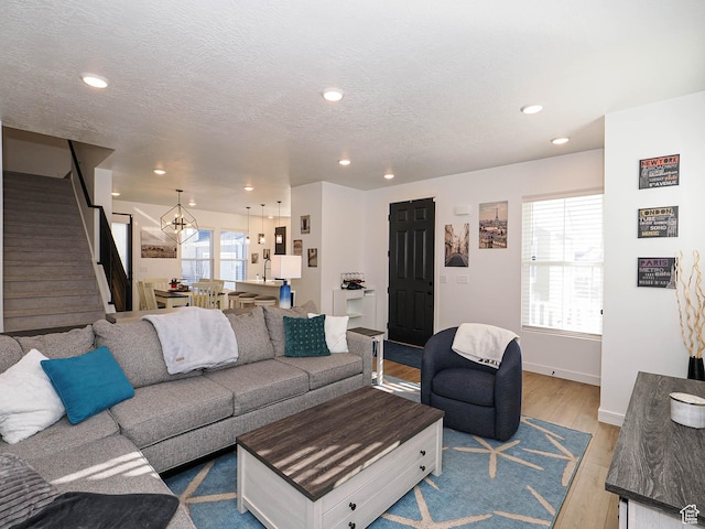 living room with light wood-style floors, recessed lighting, a textured ceiling, and stairs