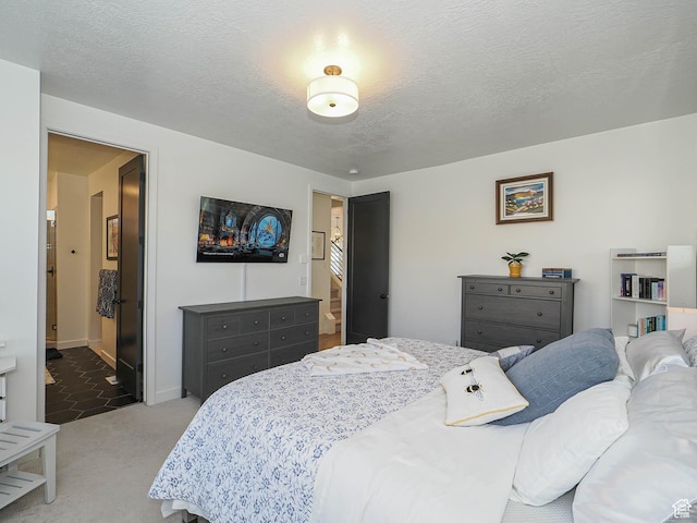 bedroom with a textured ceiling, ensuite bathroom, carpet flooring, and baseboards