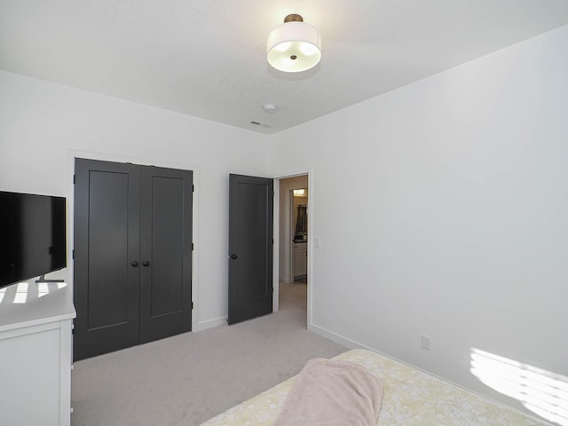 bedroom with baseboards, a closet, and light colored carpet