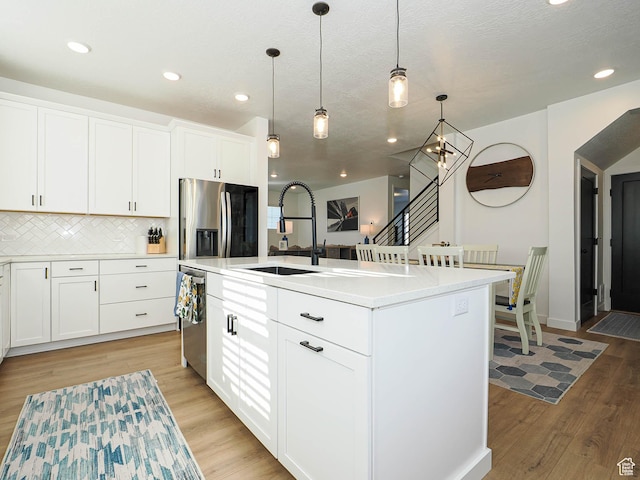 kitchen featuring decorative light fixtures, tasteful backsplash, light countertops, appliances with stainless steel finishes, and light wood-type flooring