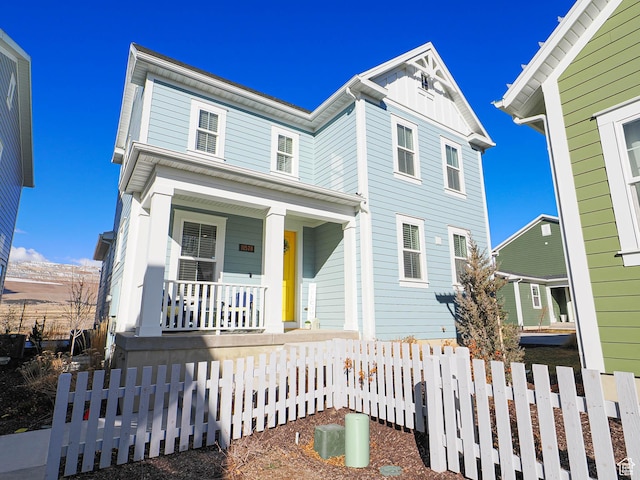 view of front of home with covered porch, a fenced front yard, and board and batten siding