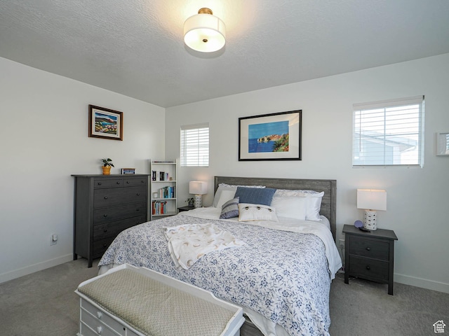 bedroom with light carpet, a textured ceiling, and baseboards