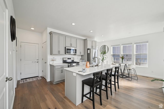 kitchen featuring stainless steel appliances, a breakfast bar, dark wood finished floors, and gray cabinetry