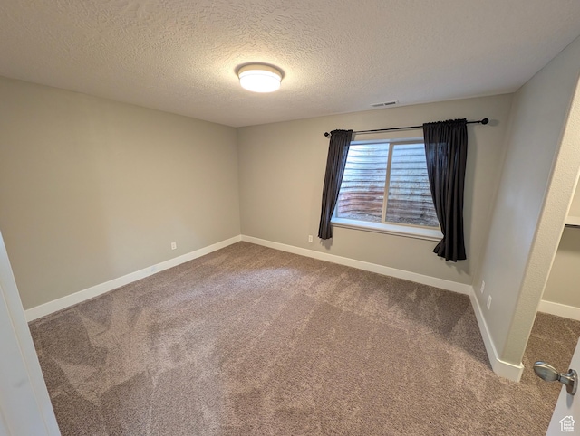 empty room featuring carpet floors, a textured ceiling, and baseboards