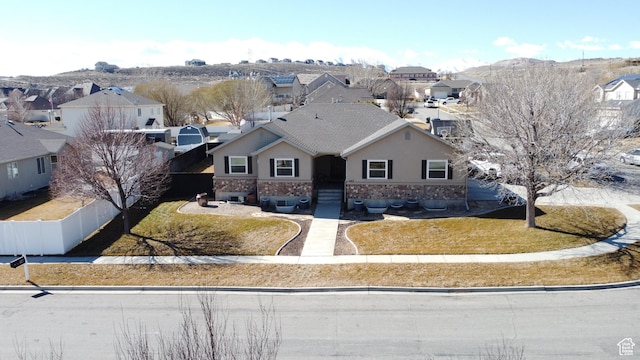 view of front of house featuring a residential view, stucco siding, fence, and stone siding