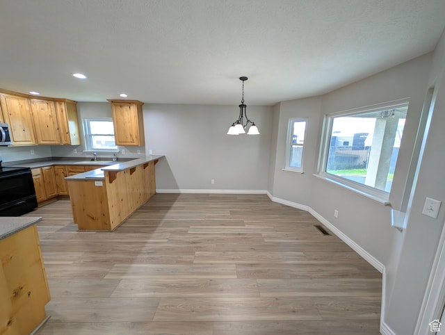 kitchen with black range with electric cooktop, a peninsula, light wood-style flooring, recessed lighting, and baseboards