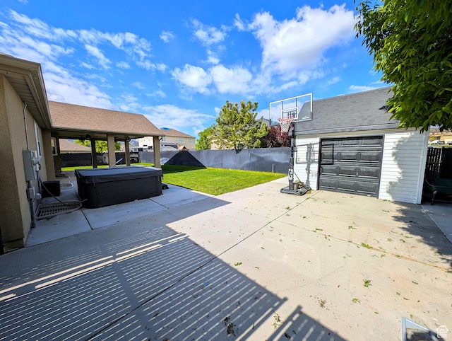 view of patio with a hot tub, a garage, an outdoor structure, and driveway