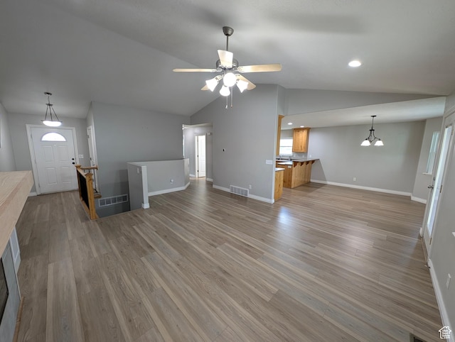 unfurnished living room with lofted ceiling, baseboards, light wood-style flooring, a ceiling fan, and a chandelier