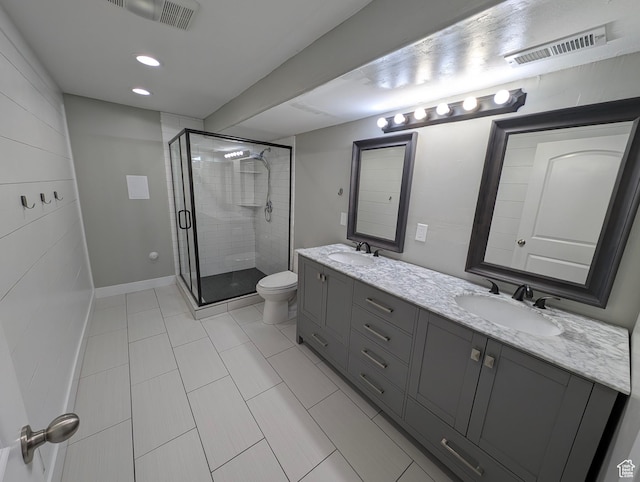 bathroom featuring toilet, a shower stall, tile patterned flooring, double vanity, and baseboards