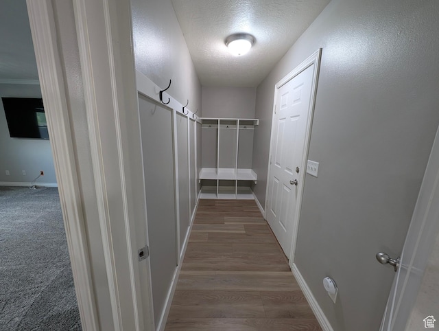 hall featuring baseboards, a textured ceiling, and wood finished floors