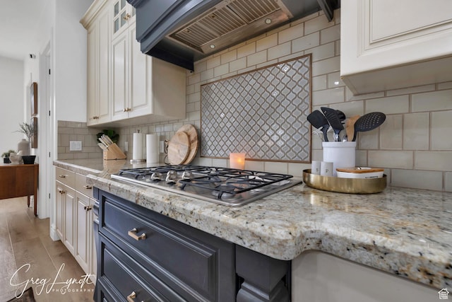 395 W Granite Dr, Washington, UT 84780 - kitchen with stainless steel gas stovetop, premium range hood, tasteful backsplash, glass insert cabinets, and light stone countertops