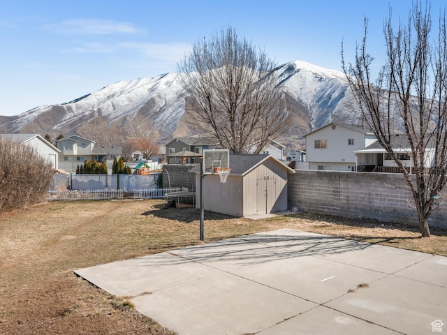 exterior space featuring a storage shed, a fenced backyard, a residential view, an outdoor structure, and a mountain view