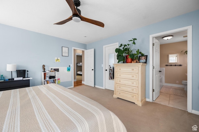 bedroom featuring light carpet, ceiling fan, baseboards, and ensuite bathroom