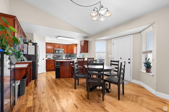 dining area with light wood-style floors, lofted ceiling, baseboards, and an inviting chandelier