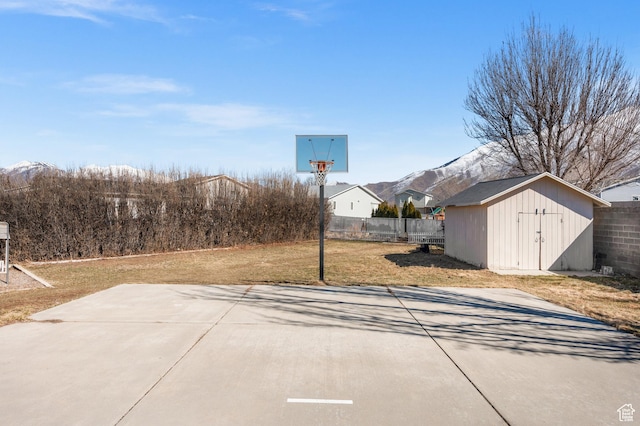 view of patio / terrace featuring a storage unit, fence, a mountain view, and an outbuilding