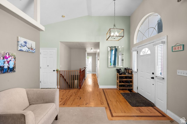 foyer with high vaulted ceiling, baseboards, and wood finished floors