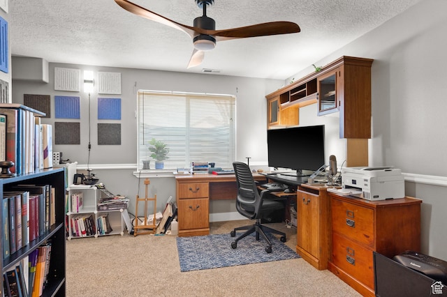 carpeted home office featuring a textured ceiling and a ceiling fan
