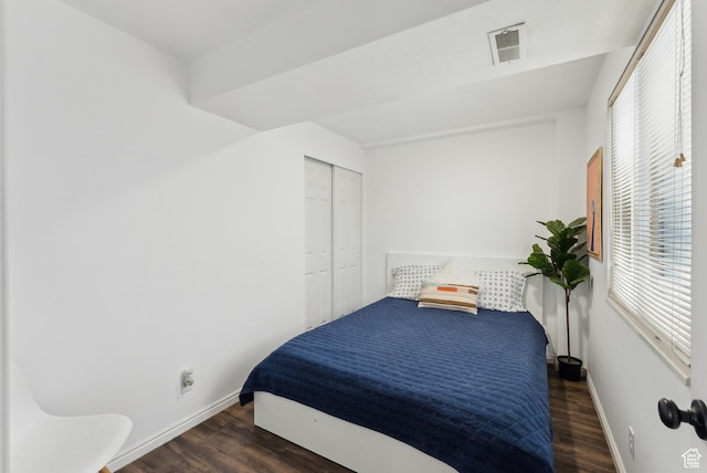 bedroom with baseboards, visible vents, and wood finished floors