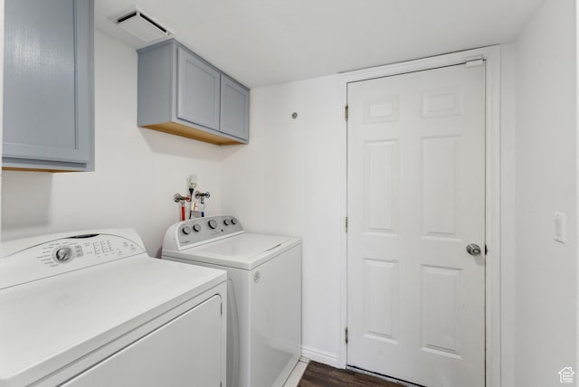 laundry room with cabinet space, baseboards, visible vents, dark wood-type flooring, and washer and dryer