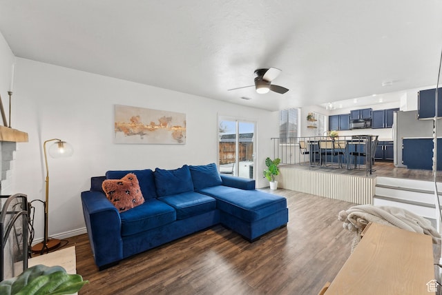 living room featuring baseboards, dark wood finished floors, and a ceiling fan