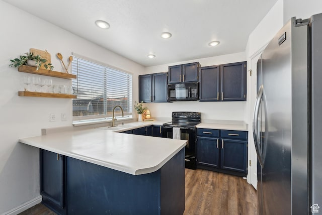 kitchen with a peninsula, a sink, light countertops, dark wood-style floors, and black appliances