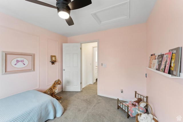 carpeted bedroom featuring baseboards, attic access, and a ceiling fan