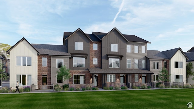 townhome / multi-family property featuring board and batten siding, brick siding, and a front lawn
