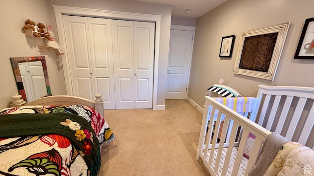 bedroom with a closet, light colored carpet, and baseboards
