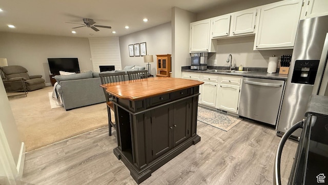 kitchen with dark countertops, light wood-style flooring, stainless steel appliances, a sink, and recessed lighting