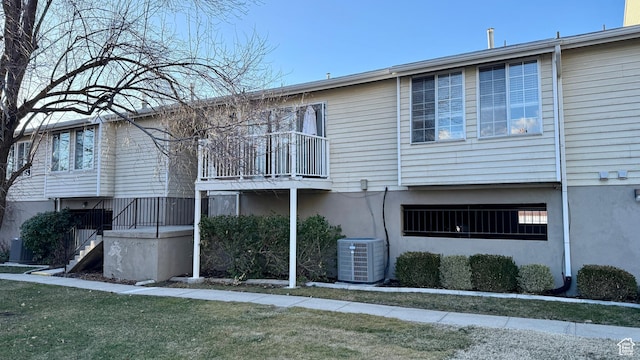 back of property featuring central AC, a yard, stairway, and a balcony