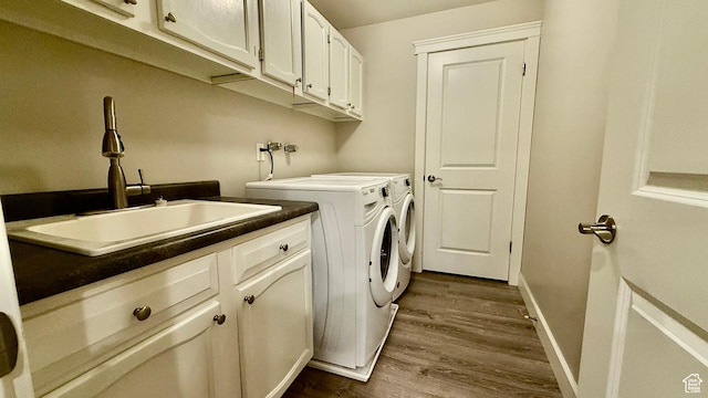 washroom with cabinet space, dark wood-type flooring, a sink, independent washer and dryer, and baseboards
