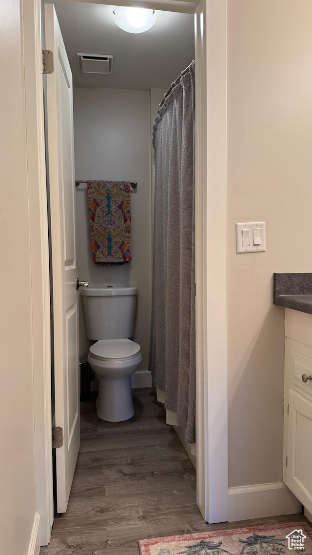 bathroom with toilet, wood finished floors, vanity, visible vents, and baseboards