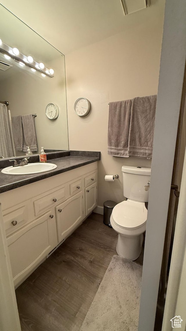 bathroom featuring toilet, visible vents, wood finished floors, and vanity
