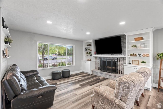 2490 W 12195 S, Riverton, UT 84065 - living room with a brick fireplace, light wood finished floors, baseboards, a textured ceiling, and recessed lighting